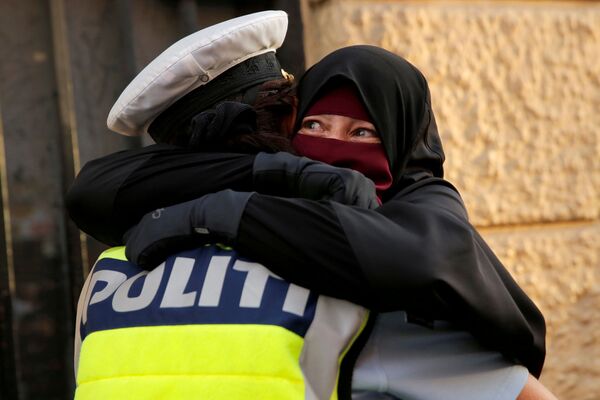 Una mujer y un policía se abrazan durante una manifestación de protesta por la entrada en vigor de la prohibición del burka en Dinamarca. - Sputnik Mundo