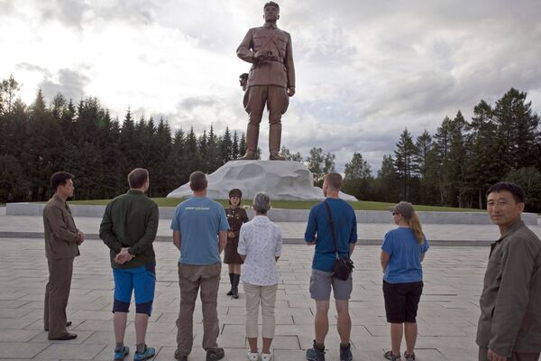 El grupo de turistas visita una escultura cerca del monte Paektu. - Sputnik Mundo