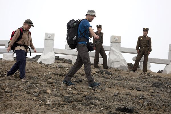 El grupo de turistas pasa al lado de unos soldados norcoreanos de camino al monte Paektu. - Sputnik Mundo