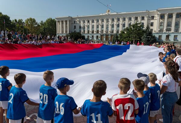 Así se celebró el 22 de agosto en Simferópol. En la foto, un grupo de menores sostiene la bandera. - Sputnik Mundo