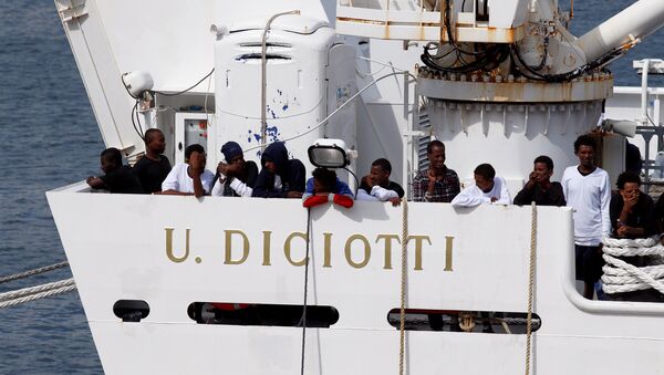Los migrantes esperan para desembarcar del barco de la guardia costera italiana Diciotti cuando llegan al puerto de Catania, Italia - Sputnik Mundo