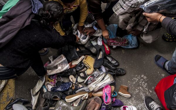 Integrantes de la segunda caravana del éxodo centroamericano buscan zapatos en buen estado que puedan utilizar - Sputnik Mundo