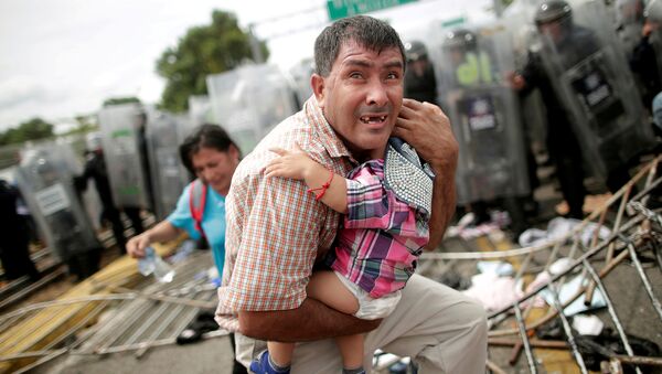 Un migrante trata desesperadamente de proteger a su bebé durante un choque en el cruce de la frontera entre México y Guatemala, el 19 de octubre de 2018 - Sputnik Mundo