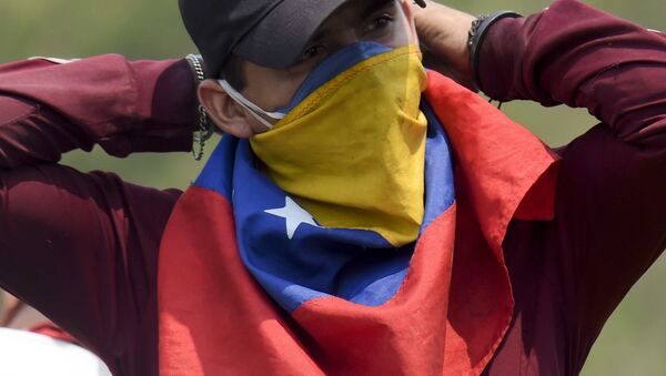 Un manifestante con la bandera de Venezuela en su cara - Sputnik Mundo