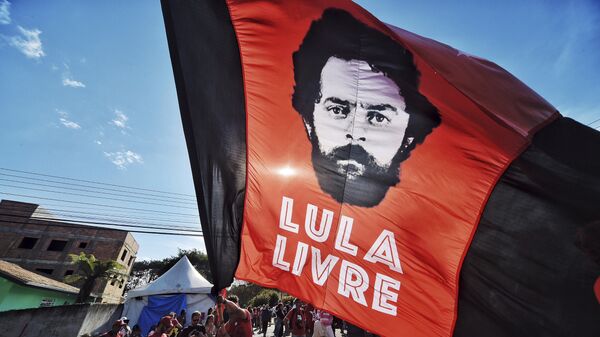 Un apoyador del expresidente de Brasil, Luiz Inácio Lula da Silva, ondea una bandera con la imagen de da Silva y un mensaje que dice Lula libre - Sputnik Mundo