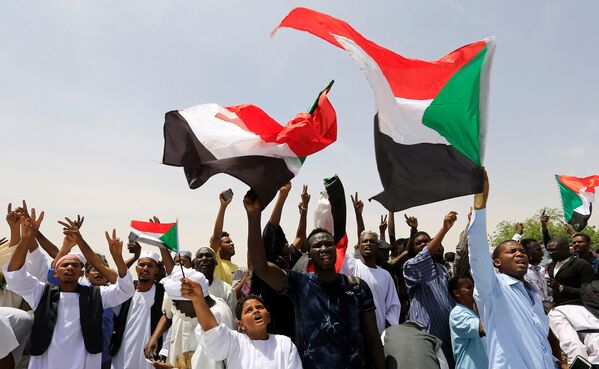 Manifestantes sudaneses ondean sus banderas nacionales y cantan consignas mientras protestan contra el anuncio del Ejército de que el presidente Omar Bashir ha sido derrocado, el 12 de abril de 2019 - Sputnik Mundo