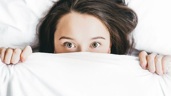 Mujer se asoma por las sábanas de una cama - Sputnik Mundo