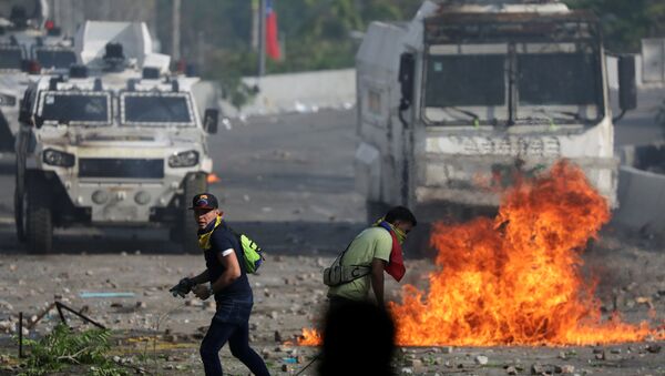 Seguidores de la oposición venezolana caminan en frente de un vehículo militar durante un enfrentamiento con las fuerzas de seguridad - Sputnik Mundo