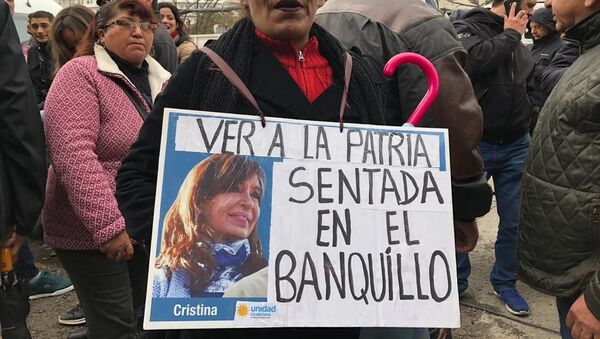 Una mujer sostiene un cartel en apoyo a Cristina Fernández durante el juicio oral en su contra - Sputnik Mundo