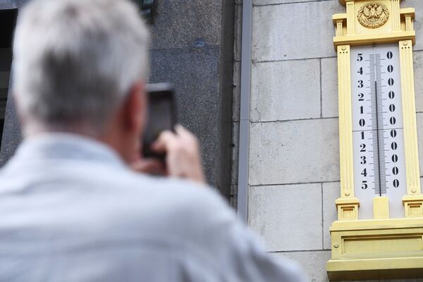 Un hombre toma la foto de un termómetro en el edificio de la Duma Estatal en Moscú. - Sputnik Mundo
