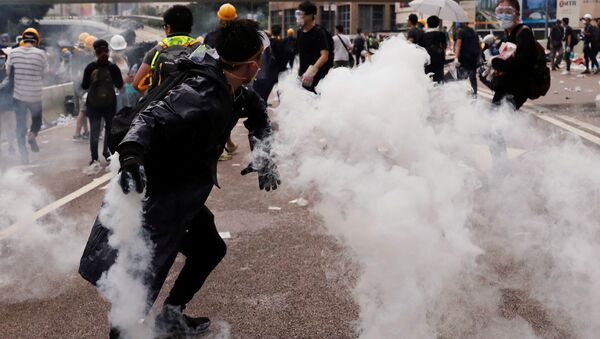 Un manifestante lanza una lata de gas lacrimógeno durante una manifestación contra un proyecto de la ley de extradición en Hong Kong, China.  - Sputnik Mundo