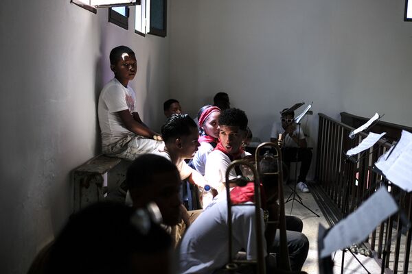 Jóvenes esperan tocar sus instrumentos durante la celebración de la misa del Día de San Juan Bautista en Curiepe. - Sputnik Mundo