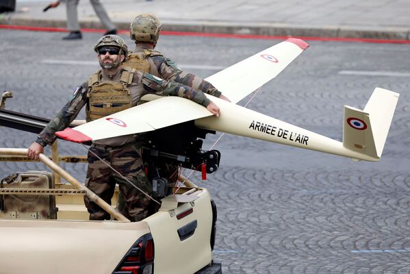 Participantes del desfile militar con un dron en los Campos Elíseos de París.  - Sputnik Mundo