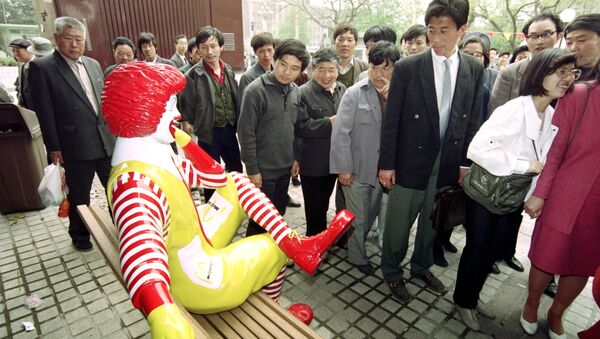 Unos chinos pasan al lado de una estatua de McDonalds - Sputnik Mundo