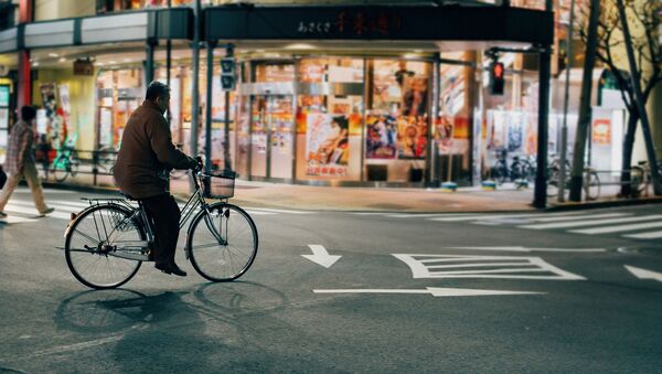 Hombre andando en bicicleta en Tokio - Sputnik Mundo