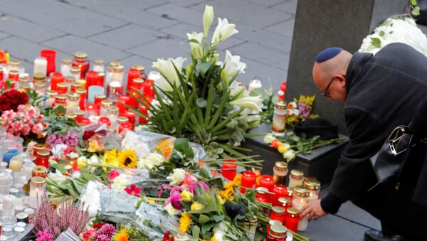 Una persona pone una vela en homenaje al tiroteo en la plaza de Halle - Sputnik Mundo