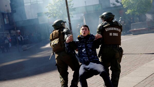 Carabineros de Chile atrapan a un manifestante durante una protesta - Sputnik Mundo