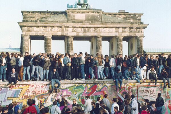 Alemanes de ambos lados se paran en el Muro de Berlín frente a la Puerta de Brandenburgo  - Sputnik Mundo