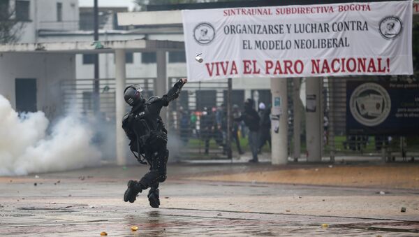 Un policía arroja una bomba de gas a manifestantes durante el paro nacional del 21 de noviembre de 2019 en Bogotá - Sputnik Mundo