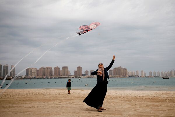 Женщина в мусульманской одежде с воздушным змеем на пляже в Дохе, Катар - Sputnik Mundo