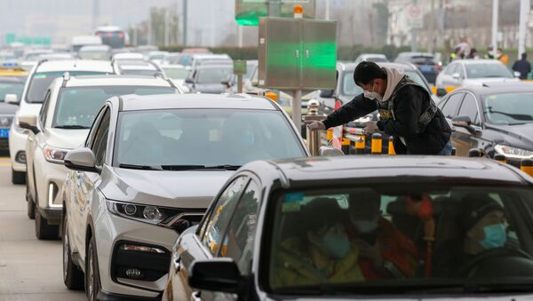 Сотрудник группы по санитарии и профилактике эпидемий проверяет температуру тела пассажира в автомобиле на стоянке в Ухане, Китай - Sputnik Mundo