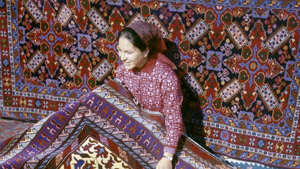Una mujer posa con alfombras hechas artesanalmente en Daguestán (1970) - Sputnik Mundo