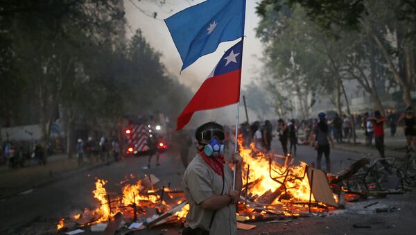Manifestante con bandera de Chile y bandera mapuche en una barricada - Sputnik Mundo