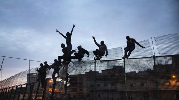Inmigrantes subsaharianos trepan por la valla de Melilla (archivo) - Sputnik Mundo