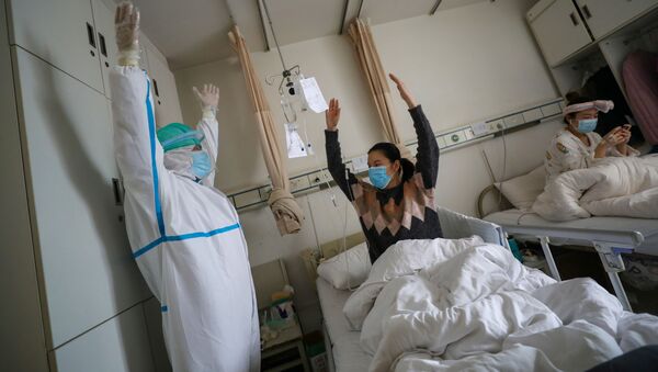 Un médico junto a una paciente en un hospital de Wuhan, China - Sputnik Mundo