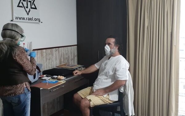 David Uzal en su habitación de hotel en Caracas mientras una doctora le realiza las pruebas para saber si tiene coronavirus - Sputnik Mundo