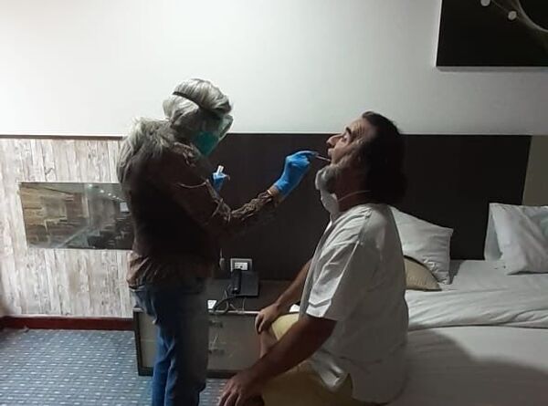 David Uzal en su habitación de hotel en Caracas mientras una doctora le realiza las pruebas para saber si tiene coronavirus - Sputnik Mundo