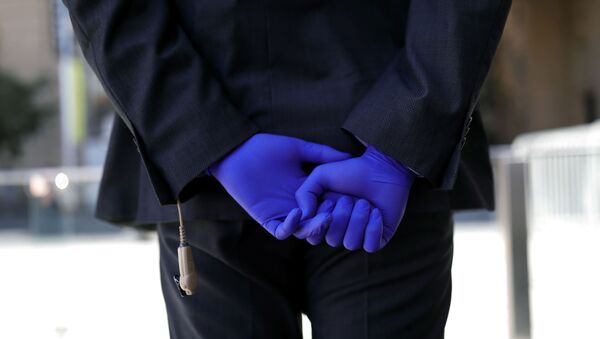 Una persona con guantes en Chile durante el brote de coronavirus - Sputnik Mundo