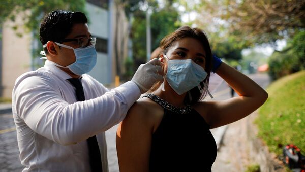 Un chico y una chica con mascarillas durante el brote del coronavirus en El Salvador - Sputnik Mundo