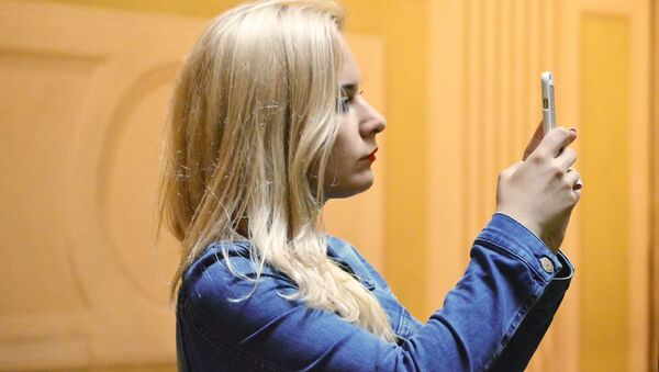Una chica haciendo una foto con un teléfono móvil  - Sputnik Mundo