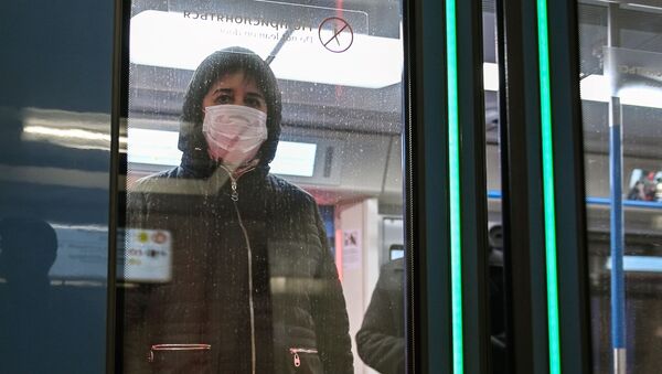 Женщина в защитной маске в вагоне поезда на станции метро Новокузнецкая в Москве - Sputnik Mundo