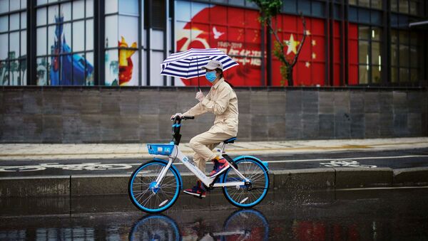 Una mujer en bicicleta con la bandera china en el fondo - Sputnik Mundo