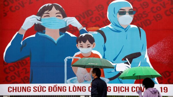 Personas con mascarillas pasan al lado de una pintura que promueve la prevención contra el COVID-19 en Hanoi, Vietnam - Sputnik Mundo