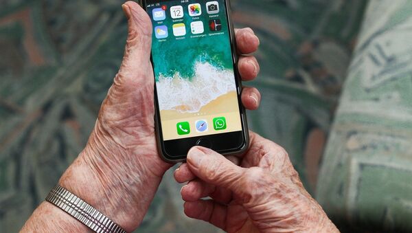 Un teléfono móvil en manos de una persona mayor  - Sputnik Mundo