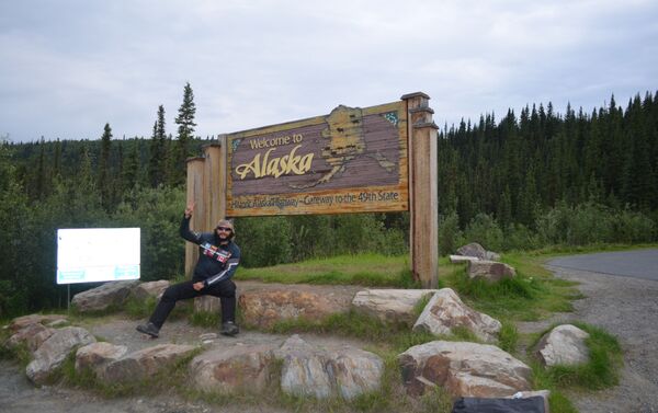 El MotoNauta en Alcan, en el cartel de bienvenida que está al salir de los territorios del norte de Canadá y entrar a Alaska, en la frontera con Yukon - Sputnik Mundo