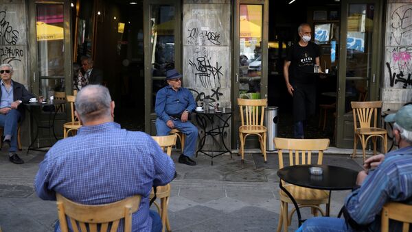 Un camarero sirve a los clientes de una cafetería el día que los restaurantes vuelven a abrir en Atenas tras el 'lockdown' por el COVID-19 - Sputnik Mundo