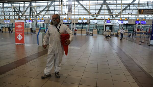 Una persona con traje protector en el aeropuerto de Santiago - Sputnik Mundo