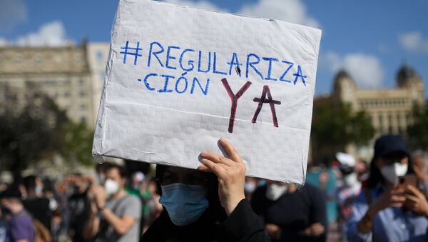Un hombre sostiene una pancarta durante la manifestación por los migrantes en Barcelona - Sputnik Mundo