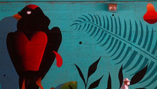 Un hombre en mascarilla pasa al lado de un muro con graffiti en Madrid - Sputnik Mundo