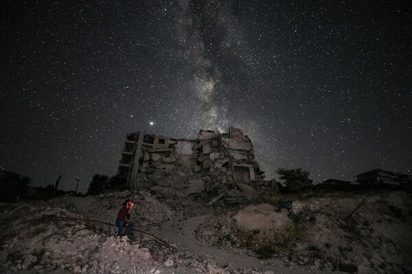 Разрушенные в результате бомбардировки здания на фоне звездного неба в сирийской провинции Идлиб - Sputnik Mundo