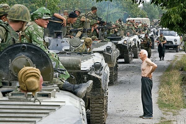 Un convoy de militares rusos camino a una base provisional en el territorio de Georgia, el 16 de agosto de 2008. A la derecha, un hombre georgiano. - Sputnik Mundo