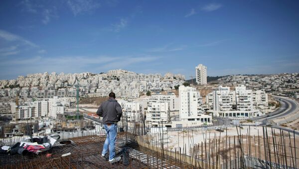 A labourer stands on an apartment building under construction in a Jewish settlement known to Israelis as Har Homa and to Palestinians as Jabal Abu Ghneim, in an area of the West Bank that Israel captured in a 1967 war and annexed to the city of Jerusalem, October 28, 2014. - Sputnik Mundo